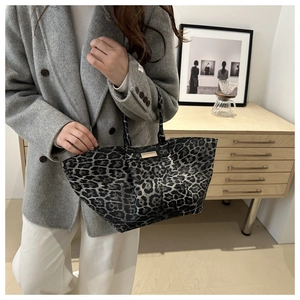 Leopard print tote bag with metal hardware detail shown on model in a modern room