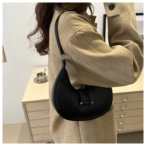 Side view of a black half-moon shoulder bag with silver buckle on a female model