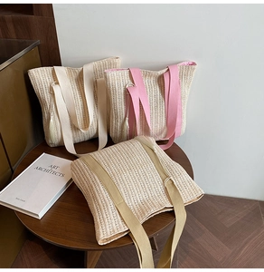 Dettaglio di borse tote in paglia intrecciata con nappe colorate e ampie tracolle in tessuto
