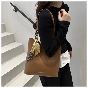 Détail d'un cabas en cuir marron avec anse en foulard de soie et texte imprimé