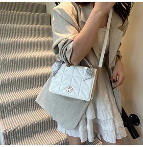 Detail of white quilted crossbody bag with silver buckle and printed silk scarf handle