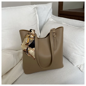 Detail of khaki tote bag featuring printed silk scarf and fashion embossed text logo