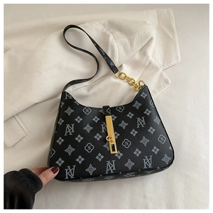 Close-up of retro printed black baguette bag with gold chain and AN floral pattern