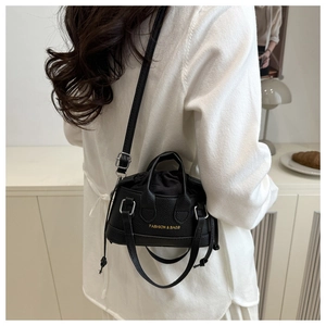 Rear view of a model wearing the black lychee pattern PU leather crossbody bag indoors