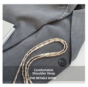 Detail of woven white leather and gold metal chain strap on grey twill fabric
