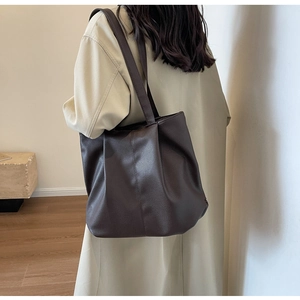 Gros plan d'un grand sac cabas marron café au grain de litchi porté par un mannequin