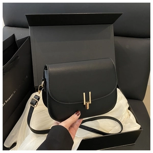 Detail of a black leather saddle bag with gold metal clasp in a gift box with silk fabric