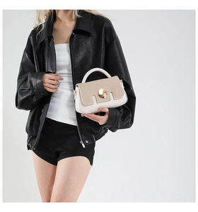 Détail d'un sac bandoulière crème avec texture tressée et boucle métallique dorée