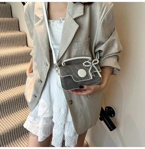 Détail du sac à bandoulière gris avec nœud en perles et pendentif en cœur