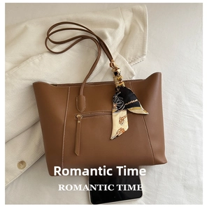 Detailed view of brown leather tote bag with white contrast stitching and printed silk scarf