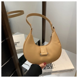 Close-up of beige crescent shoulder bag with matte leather finish and silver hardware