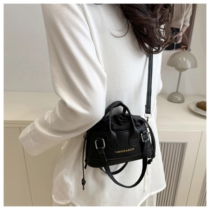 Detail view of mini black leather handbag featuring golden FASHION & BAGS logo and strap