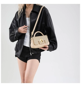Détail du sac bandoulière beige en cuir et tissu avec une boucle ronde en métal doré