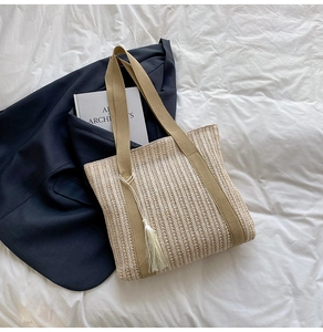 Dettaglio della borsa in paglia intrecciata a righe verticali con nappa beige