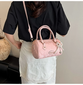 Pink snake-embossed pillow bag with pearl bow pendant shown in a lifestyle modeling shot