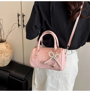 Pink Boston bag detail with snake pattern texture and pearl bow charm accessory