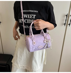 Detail of purple snakeskin pattern pillow bag with pearl bow charm on shoulder
