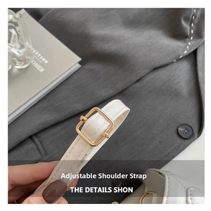Detail of adjustable white leather strap with polished gold square buckle on shoulder bag