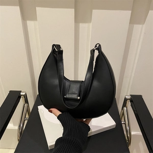 Minimalist black crescent moon shoulder bag in matte leather held by person