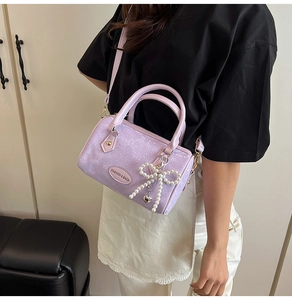 Detail of light purple snakeskin pattern Boston bag with pearl bow and logo plaque
