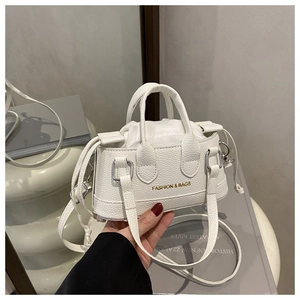 Close-up of white lychee pattern leather mini shell bag with golden fashion lettering