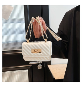 Macro detail of white quilted mini bag featuring gold chain strap and metal twist lock