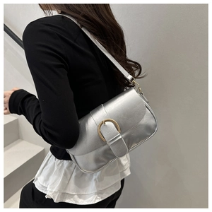 Détail d'un sac à bandoulière argenté avec finition métallique et boucle fer à cheval dorée