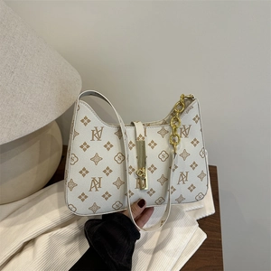 White monogram shoulder bag with gold chain and floral patterns in a cozy setting
