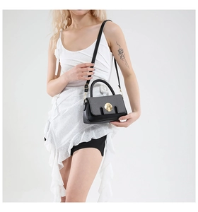 Détail d'un sac à main en cuir noir avec fermoir doré rotatif et fine bandoulière