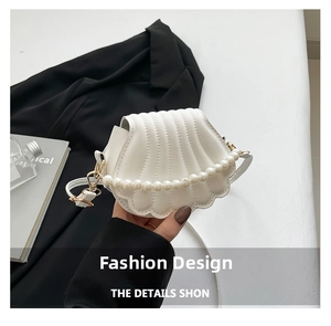 Close-up of white shell shaped bag with quilted texture and large pearl chain detail