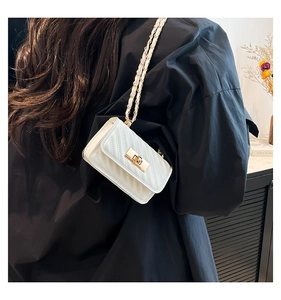 Detail of white quilted mini bag with gold chain strap and V-shaped stitching on model