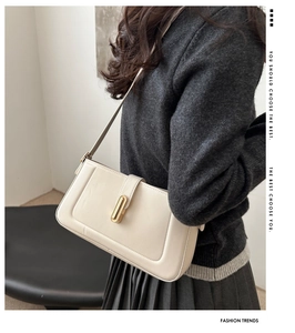 Détail du sac à épaule en cuir crème avec boucle dorée porté par un mannequin