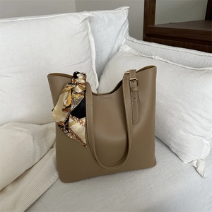 Khaki Tote Bag mit Seidenschal auf weißem Sofa, minimalistische große Schultertasche
