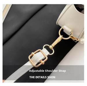 Detail of adjustable faux leather shoulder strap with gold-tone hardware on white shell bag