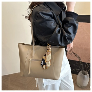 Detail of khaki leather tote bag featuring a vintage chain print silk scarf and front pocket