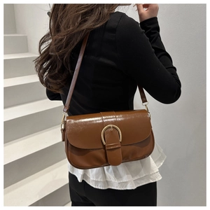 Détail d'un sac besace marron vintage avec boucle dorée porté par un mannequin femme