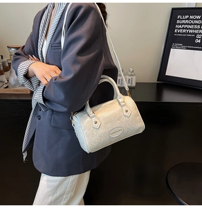 Detail of white Boston handbag with crocodile pattern being worn as a crossbody bag