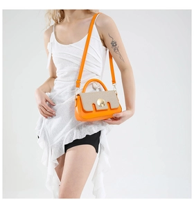 Detail view of stylish orange and beige patchwork crossbody bag with gold buckle hardware