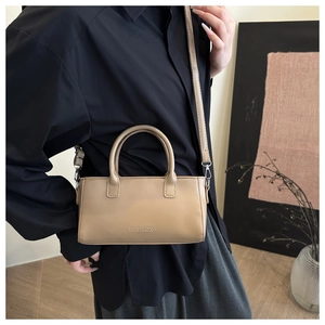 Détail du sac à main beige minimaliste avec texte embossé et fine bandoulière sur mannequin