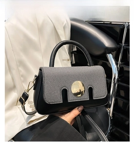 Detail of black crossbody bag with grey woven texture flap and gold circular buckle