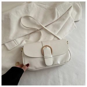 Détail du sac selle en cuir crème avec boucle en fer à cheval dorée élégante