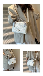 Détail d'un sac matelassé blanc avec fermoir doré et poignée ornée d'un foulard