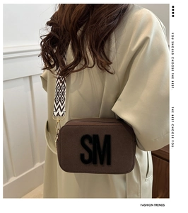 Detail of a dark brown crossbody bag with 3D SM logo and ethnic pattern wide strap