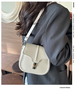 Back view of a model wearing a beige leather saddle bag with a gold buckle clasp