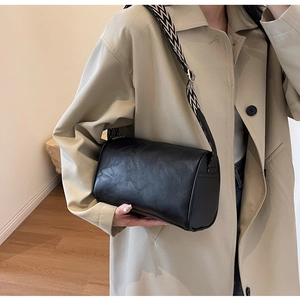 Details einer schwarzen Zylindertasche mit einem schwarz-weiß gemusterten breiten Tragegurt