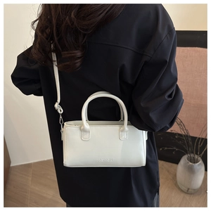 Dettaglio mini borsa in pelle bianca con scritta a rilievo e finiture metalliche