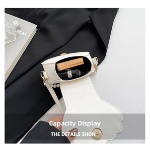 Detail of white wave-cut crossbody bag showing pearl chain and compact interior capacity