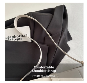 Close-up of a white leather shoulder bag strap against a black suit for office style