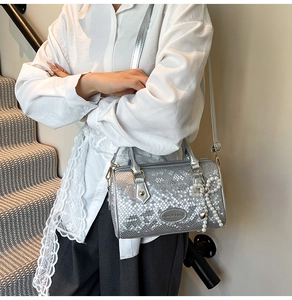 Detail of silver snake-pattern Boston bag with pearl bow charm and metal brand tag