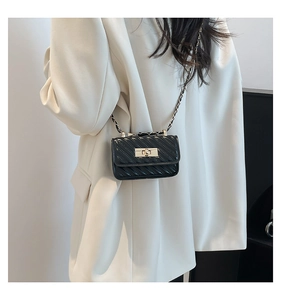 Mini black quilted crossbody bag with gold clasp shown on model for size and style